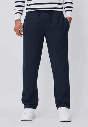 Pantalon de survêtement bleu marine en tissu doux, avec une taille élastique et un cordon de serrage, des poches latérales et une coupe décontractée.
