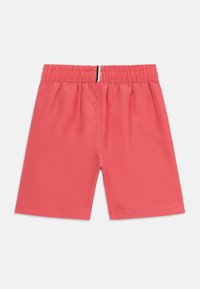 Ελαστικά σορτς κοραλλί με μικρή κάθετη λεπτομέρεια ριγέ σε μαύρο, μπεζ και καφέ στο κέντρο της πίσω μέσης.