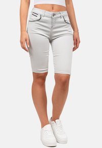 Bermuda shorts in denim grigio con design aderente, cuciture a contrasto e due tasche anteriori con dettagli neri. Indossati con sneakers bianche.