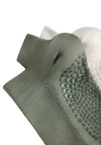 Par čarapa s teksturom u maslinastoj zelenoj i krem boji. Sadrže rebrasti dizajn i silikonske točkice za stabilnost. Mekani pleteni materijal.