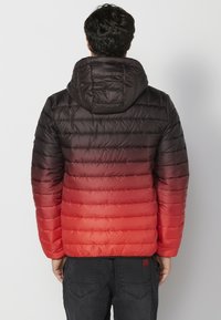 Giubbotto puffa con cappuccio, sfumato dal nero al rosso, con sezioni trapuntate e una texture liscia e lucida.
