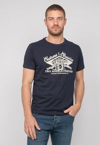 T-shirt en coton bleu marine avec un design graphique comportant le texte "Detroit". Manches courtes, col rond, texture douce et coupe décontractée.