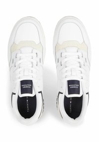 Białe sneakersy z gładką skórzaną cholewką i tekstylnymi akcentami. Posiadają szare i beżowe detale, sznurówki oraz teksturowaną kauczukową podeszwę.