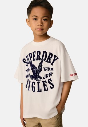 Hvid bomulds t-shirt med et navy grafisk print af en ørn og teksten "SUPERDRY EAGLES". Korte ærmer, afslappet pasform med røde detaljer.