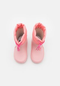 Stivali impermeabili rosa con un colletto morbido e imbottito. Presentano una superficie testurizzata, lacci rosa e un elemento decorativo sul lato.