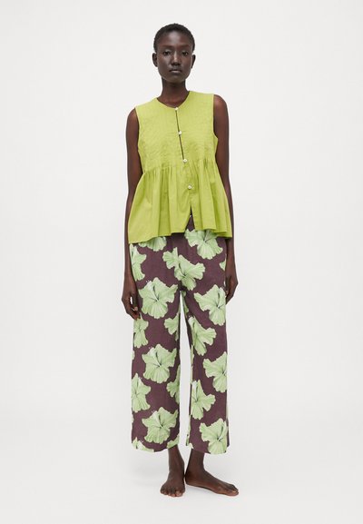 Green, sleeveless peplum top with a button front; paired with wide, high-waisted pants featuring large light green floral patterns on a dark background.