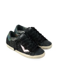 Un paio di sneakers nere basse con lati glitterati, lacci neri, suole bianche e un dettaglio a chevron metallico su ciascun lato.