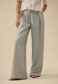 Light gray wide-leg trousers made of textured fabric, featuring a pinstripe pattern and a high waist design, paired with simple sandals.