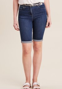 Donkerblauwe denim bermuda shorts met opgerolde mouwen, voorzien van voorzakken en een riem met een geweven patroon.