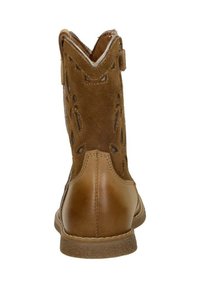 Brown leather ankle boot with a suede upper, decorative cutouts, a rounded toe, and a low textured rubber sole. Back view showcases stitching detail.