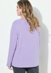 Helles lila langärmliges Shirt aus weichem Stoff, mit rundem Ausschnitt und lockerer Passform, der Saum reicht über die Hüften.