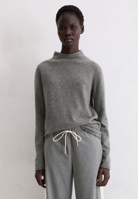 Grauer Wollpullover mit hohem Kragen und langen Ärmeln, kombiniert mit grauer Hose mit Kordelzug. Glatte Textur, lässiges Design, bequeme Passform.