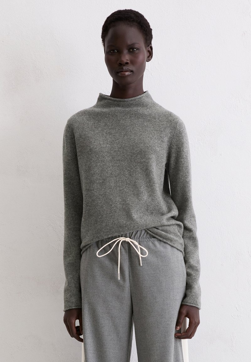 Grauer Wollpullover mit hohem Kragen und langen Ärmeln, kombiniert mit grauer Hose mit Kordelzug. Glatte Textur, lässiges Design, bequeme Passform.