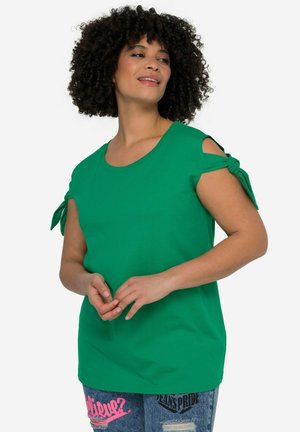Top verde a maniche corte con spalle scoperte e dettagli annodati. Realizzato in tessuto morbido, presenta un colletto rotondo e una vestibilità comoda.