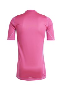 T-shirt de sport à manches courtes en rose vif, en tissu respirant avec un motif texturé, présentant des accents de couture blancs et un logo.