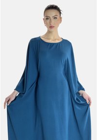 Abito lungo e fluente in tessuto blu profondo con maniche larghe e scollo rotondo, caratterizzato da una texture liscia e da una silhouette elegante.