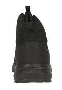 Schwarzer Sportschuh mit strukturiertem Obermaterial, gepolstertem Kragen und einer robusten Gummisohle mit ausgeprägten Traktionsstollen. Die Rückansicht zeigt die Zuglasche.