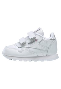 Hvit lær sneaker med to borrelåsremmer, rund tå, teksturert søm og gummisåle med små knopper for grep.