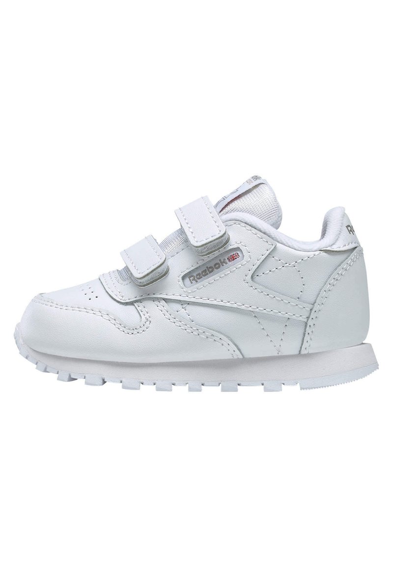 Hvit lær sneaker med to borrelåsremmer, rund tå, teksturert søm og gummisåle med små knopper for grep.