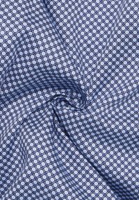 Tessuto blu con un motivo geometrico di quadrati blu navy e cerchi azzurri. Texture liscia con una lieve lucentezza.