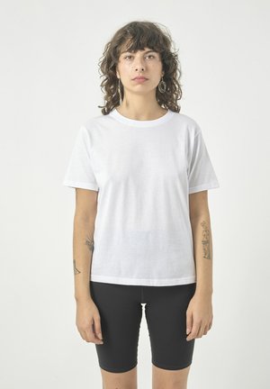White cotton t-shirt with short sleeves and a round neckline, paired with black bicycle shorts. Smooth texture, no visible patterns or graphics.