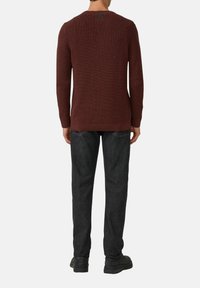 Sweter dziany w kolorze burgundowym, z teksturowanej tkaniny, z okrągłym dekoltem i długimi rękawami, w połączeniu z ciemnymi dżinsami i czarnymi botkami. Brak widocznych logotypów.