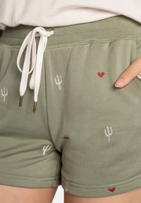 Groene katoenen shorts met witte trekkoord, voorzien van rode harten en cactussen borduursels op de stof. Zachte textuur, casual ontwerp.