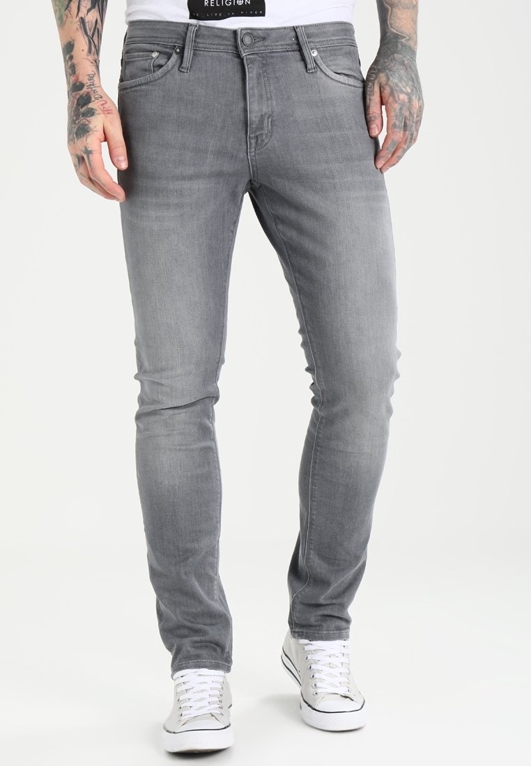 Jeans in denim grigio con una vestibilità slim, caratterizzati da cinque tasche, una chiusura a bottone e leggeri effetti di sbiadimento. Abbinati a sneaker bianche.