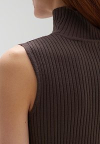 Brown ribbed knit sleeveless top with a high neck. The fabric texture is soft and the design features vertical lines.