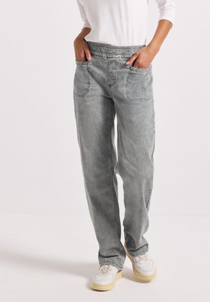 Pantalons cargo en denim gris avec ceinture élastique, poches latérales, coupe ample et texture délavée. Association avec des baskets blanches.