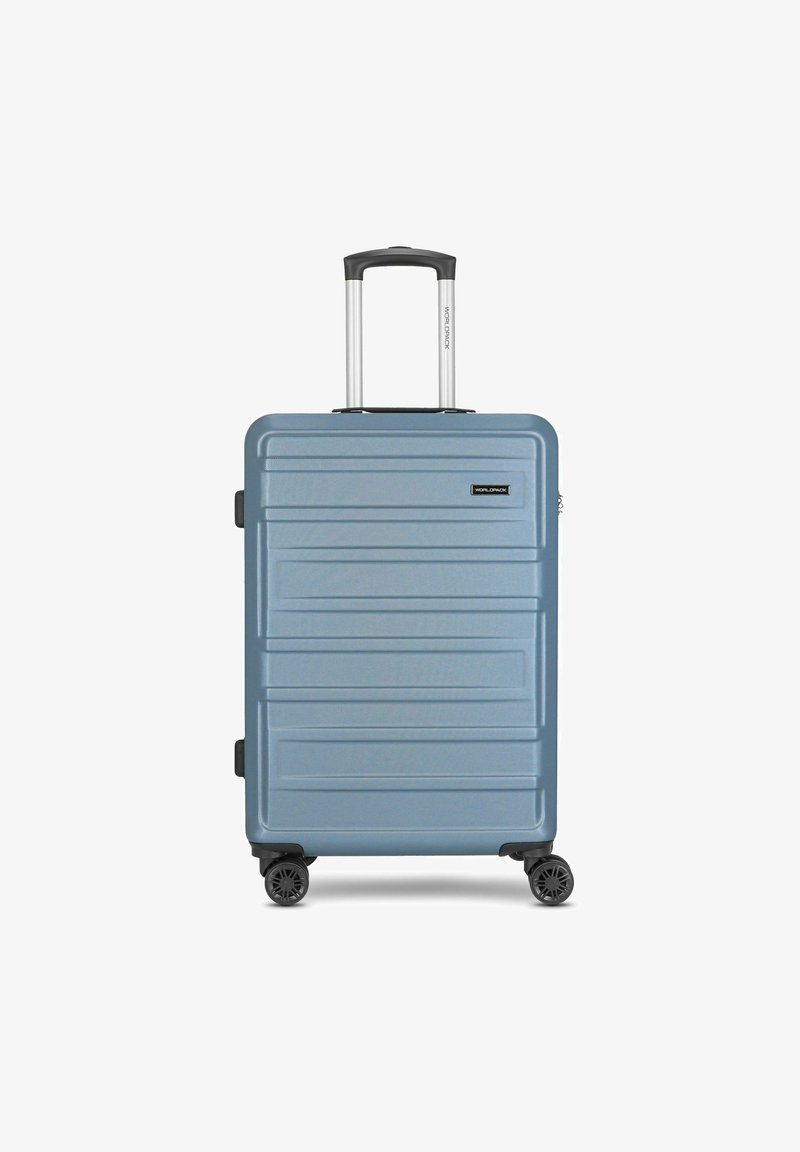 Valise rigide de couleur bleu clair, avec une surface texturée, fermeture zippée, quatre roues noires et une poignée rétractable en argent.
