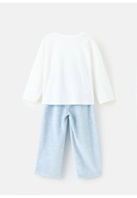 Biele tričko s dlhým rukávom v kombinácii s svetlo modrými, jemne chlpatými pyžamovými nohavicami s malými bielymi bodkami, navrhnutými pre pohodlie a teplo.