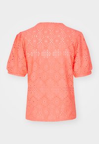 Koraalroze blouse met pofmouwen, voorzien van een geometrisch uitgesneden kantontwerp en een ronde halslijn, met een textuurdoek dat licht aanvoelt.