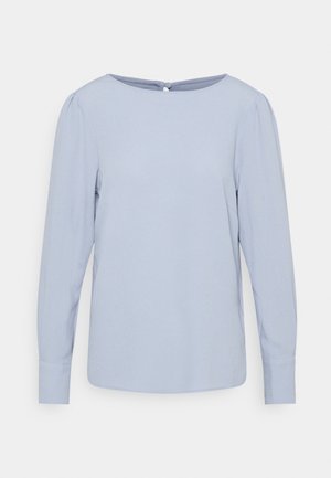 Jasnoniebieska bluzka z długim rękawem o okrągłym dekolcie, lekkie marszczenie przy ramionach, zapięcie na guziki z tyłu i dopasowane mankiety.