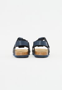 Mørkeblå sandaler med to justerbare stropper, en korksåle og en teksturert gummiyttersåle. Bakfra vises stroppe-detaljer og tekstur.