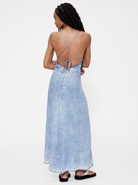 Denim maxi ruha világoskék mosással, nyitott hátrésszel, keresztben futó pántokkal és megkötő részletével, folyó szegéllyel.