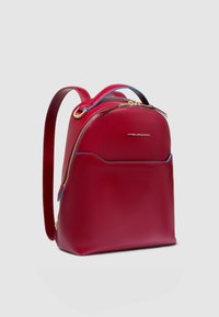 Rode leren rugzak met goudkleurige hardware, afgeronde vorm, voorvak en contrasterende blauwe accenten op het handvat en de rits.