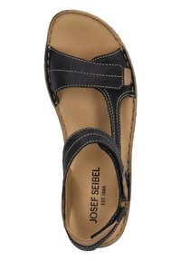 Musta nahkasandaali, jossa on litteä pohja, korostettuna ommelluilla yksityiskohdilla ja avoimella varvastyylillä. Pohjallinen on ruskea, ja brändin logo on näkyvissä.