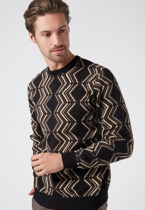 Zwart sweatshirt met een geometrisch zigzagpatroon in crème en beige. Geribbelde halslijn en manchetten. Standaard pasvorm met lange mouwen. Zachte textuur.