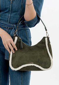 Green suede shoulder bag with white shearling trim, rounded shape, zip closure, and decorative tassels on handle.