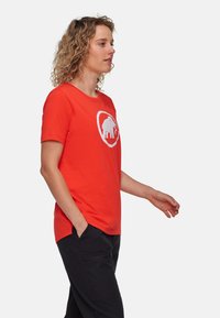 Röd kortärmad t-shirt med en vit elefantgrafik centrerad fram. Slätt tyg, avslappnad passform och rund nacke.