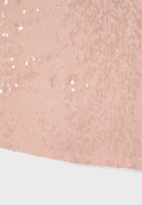 Tissu rose doux avec des paillettes brillantes dispersées créant un effet scintillant subtil sur une surface texturée.
