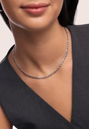 Collier en chaîne argenté avec des maillons ronds, porté autour du cou. L'arrière-plan est neutre et le vêtement est de couleur gris foncé.