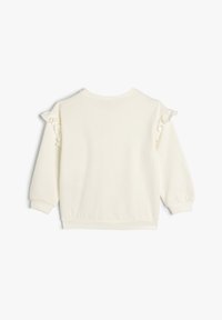 Sweatshirt couleur crème avec des manches longues, des accents froncés sur les épaules et un col et des poignets côtelés. Tissu en coton doux.