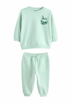 Mintgrønt sæt til småbørn med sweatshirt og bukser med ribstrikkede manchetter, der har en grafik af en smilende chokolademælkekarton på brystet af sweatshirten.