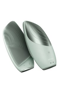 Spazzola elettrica con un corpo in plastica verde chiaro. Presenta setole testurizzate su un lato e un design liscio e curvato dall'altro.