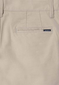 Pantalons en coton beige avec une poche arrière dotée d'une bordure brodée et d'une petite étiquette "HACKETT" en noir. Texture lisse et coupe ajustée.