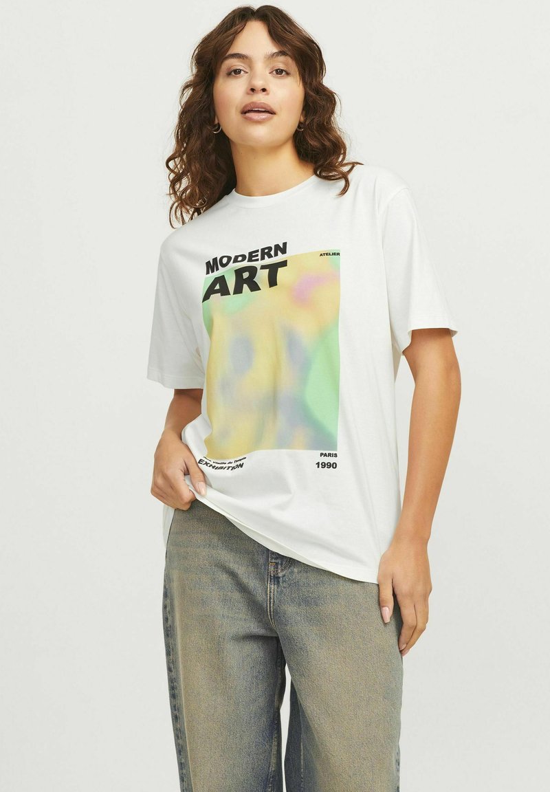 Camiseta corta de manga blanca con un gráfico de arte moderno colorido, con elementos de texto en negro. La tela parece suave y de corte relajado.