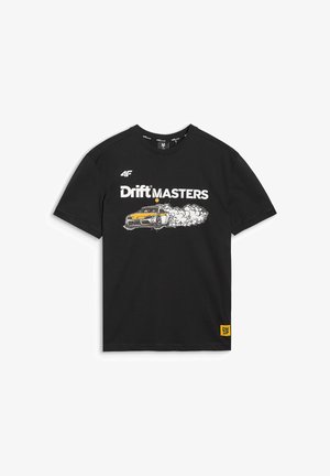 Mężczyzna w czarnej koszulce "Drift Masters" z grafiką samochodu driftingowego i czarnych spodniach typu cargo na jednolitym tle.