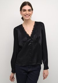Blusa nera in satin con maniche lunghe, scollatura a V decorata da pizzo intricato e chiusura con bottoni sul davanti. Tessuto liscio.